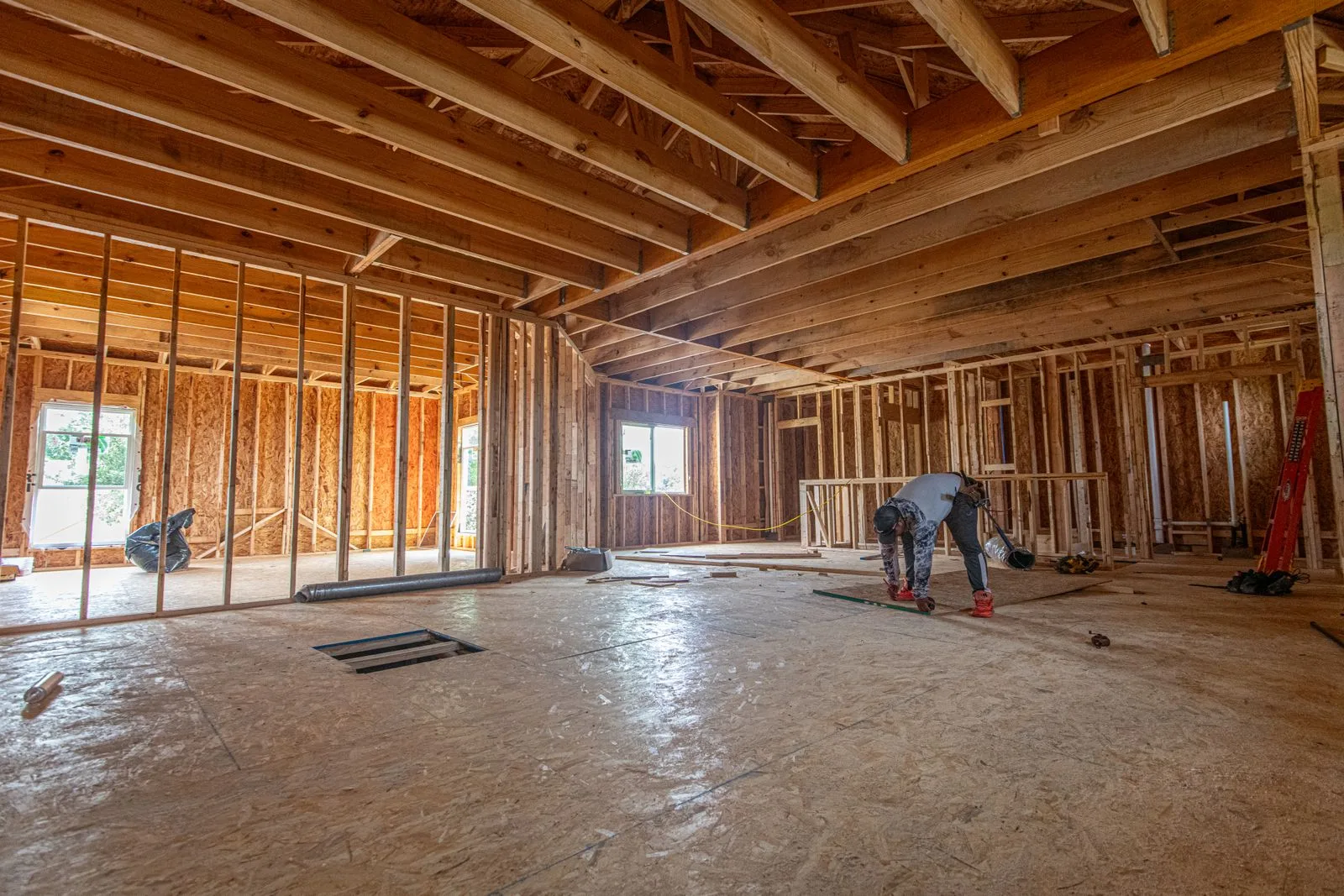 Interior of a residential home under construction — wood framing and rough-in visible before drywall